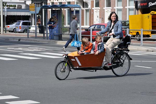 Une mère transporte ses deux enfants dans son vélo cargo