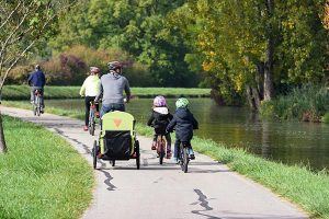 Famille à vélo avec remorque enfant le long du canal