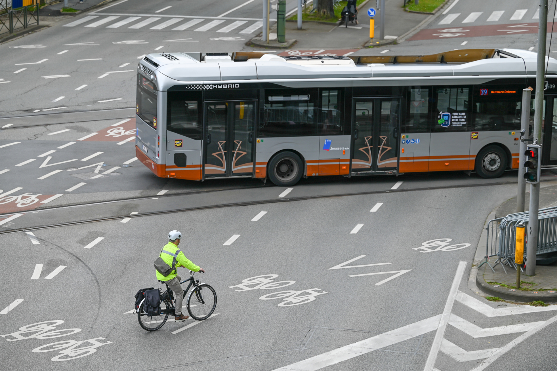 Un homme à vélo traverse une route où se trouve un bus
