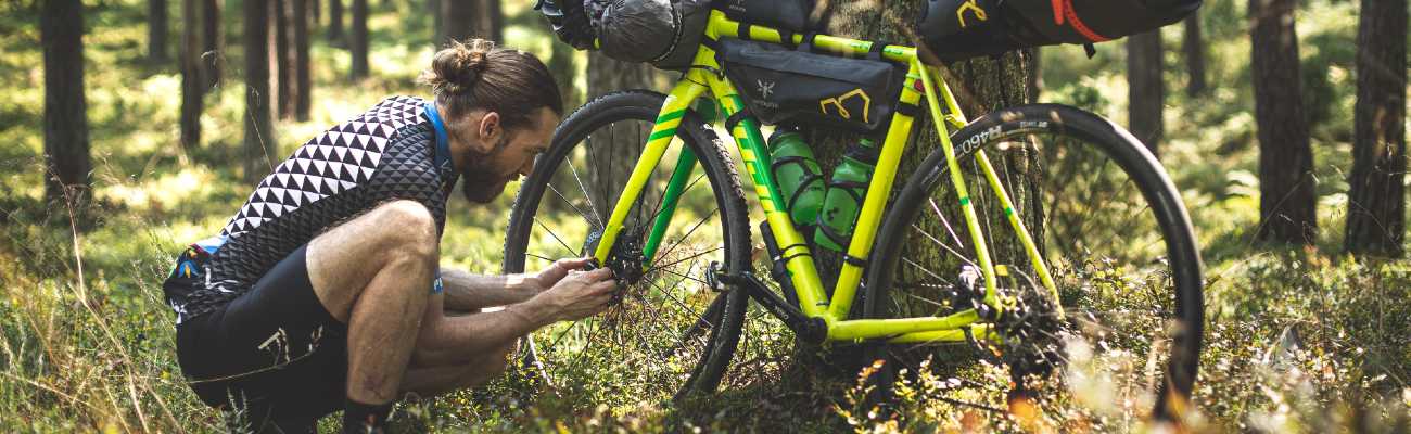 réparation en voyage à vélo par un homme lors de son trip bikepacking cyclotourisme