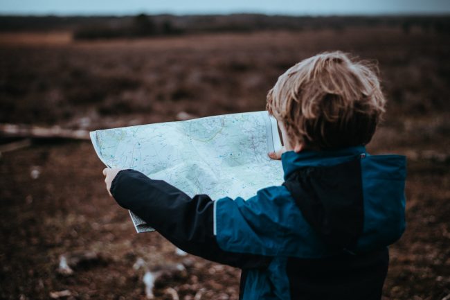 Enfant, en bivouac, tenant une carte