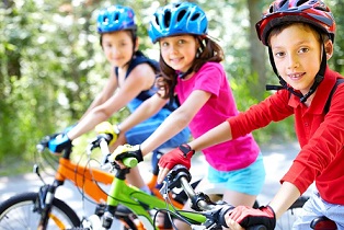 Trois enfant qui sourient à vélo.