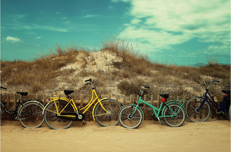 Des vélos colorés sont posé contre une dune de sable. au cours d'un voyage à vélo en famille en France.
