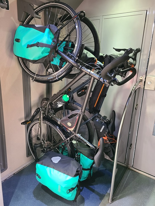 Deux vélos sont accrochés à la verticale dans l'espace vélo du train.