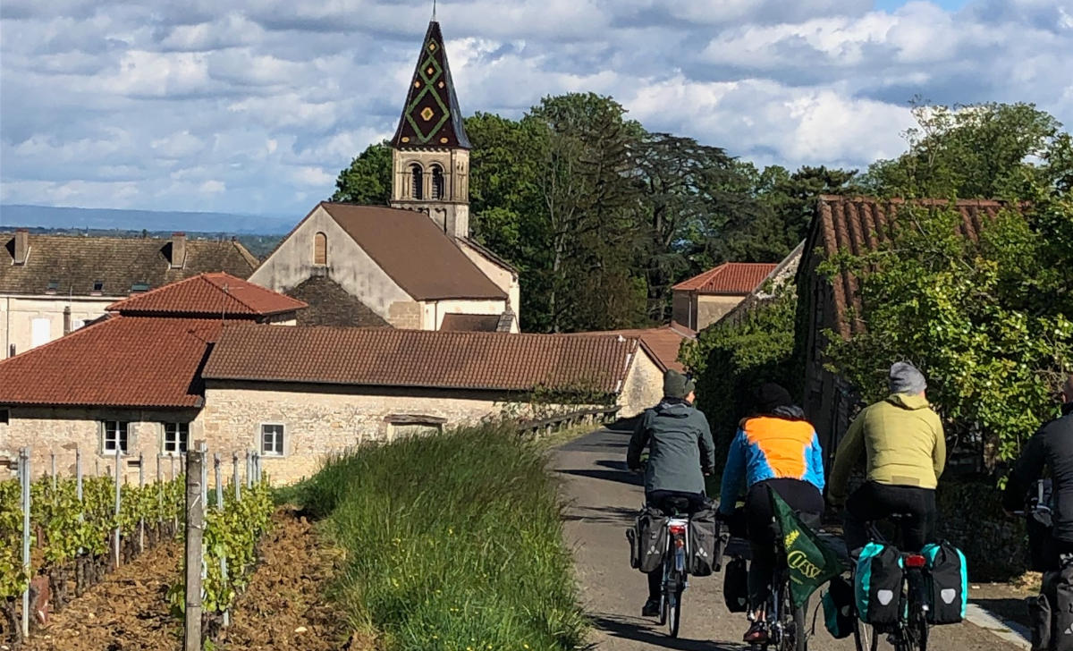 Un petite groupe de voyageurs à vélo pédalent à travers un village du Beaujolais.