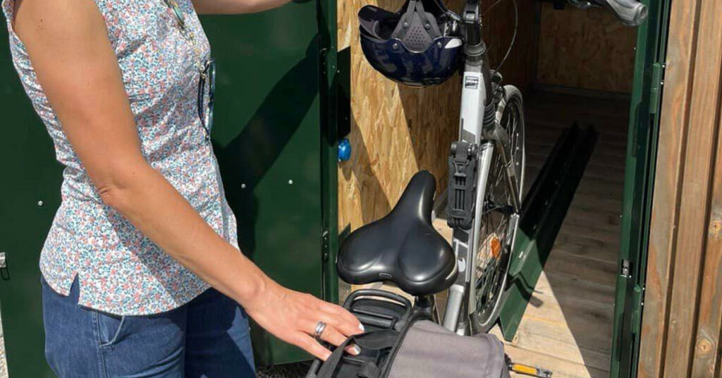 Une femme range son vélo électrique dans le casier ILOO. 