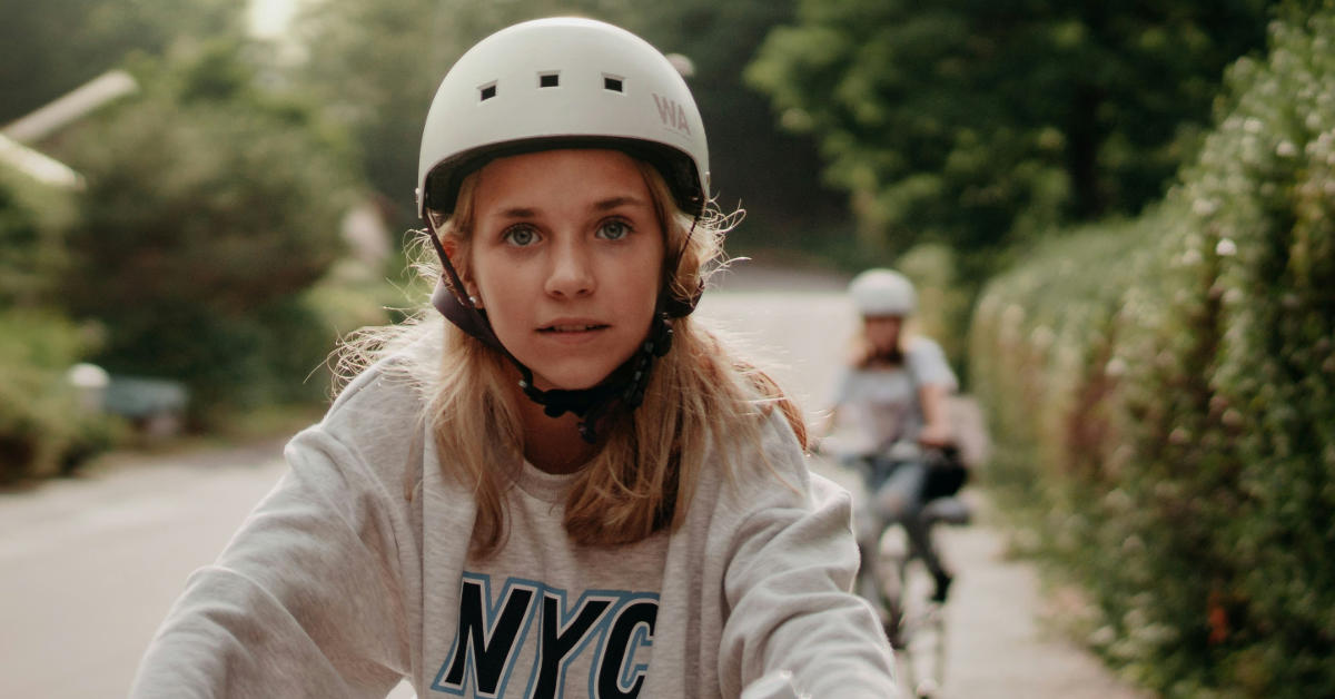 Une collégienne porte un casque de vélo et se rend au collège à vélo.