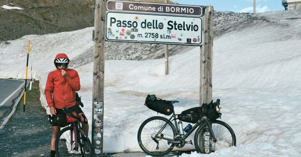 Amaury est sur vélo, en haut d'un col, il a froid et est bien couvert. De part et d'autre de la route : la neige. 