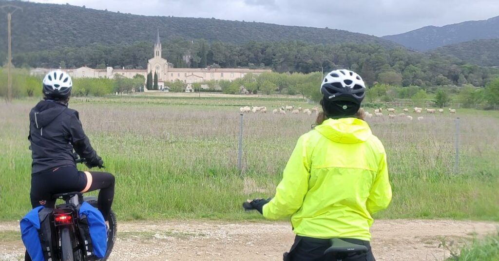 Deux cyclotouristes regardent un domaine viticole autour du Pic Saint Loup