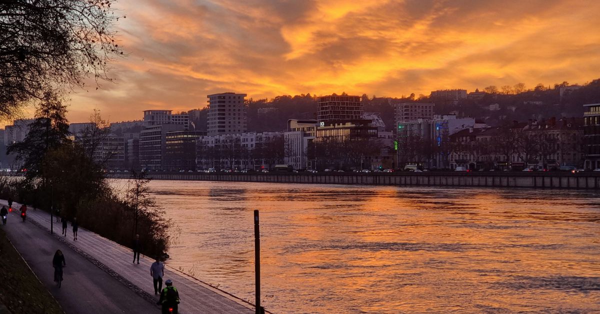 Vue au coucher du soleil sur une Voie Lyonnaise le long du fleuve, un aménagement au cœur des programmes de mobilité pour le prochain mandat municipal de 2026.