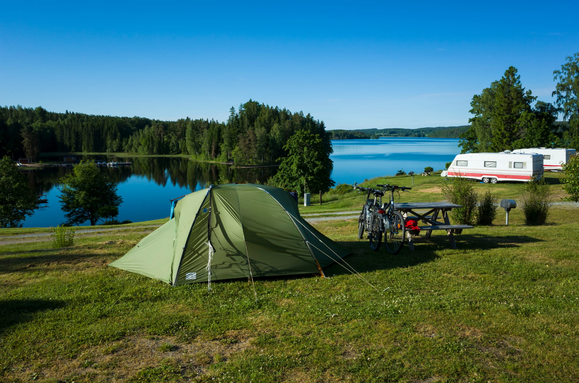 tente verte avec des vélos à côté devant un lac en Suède