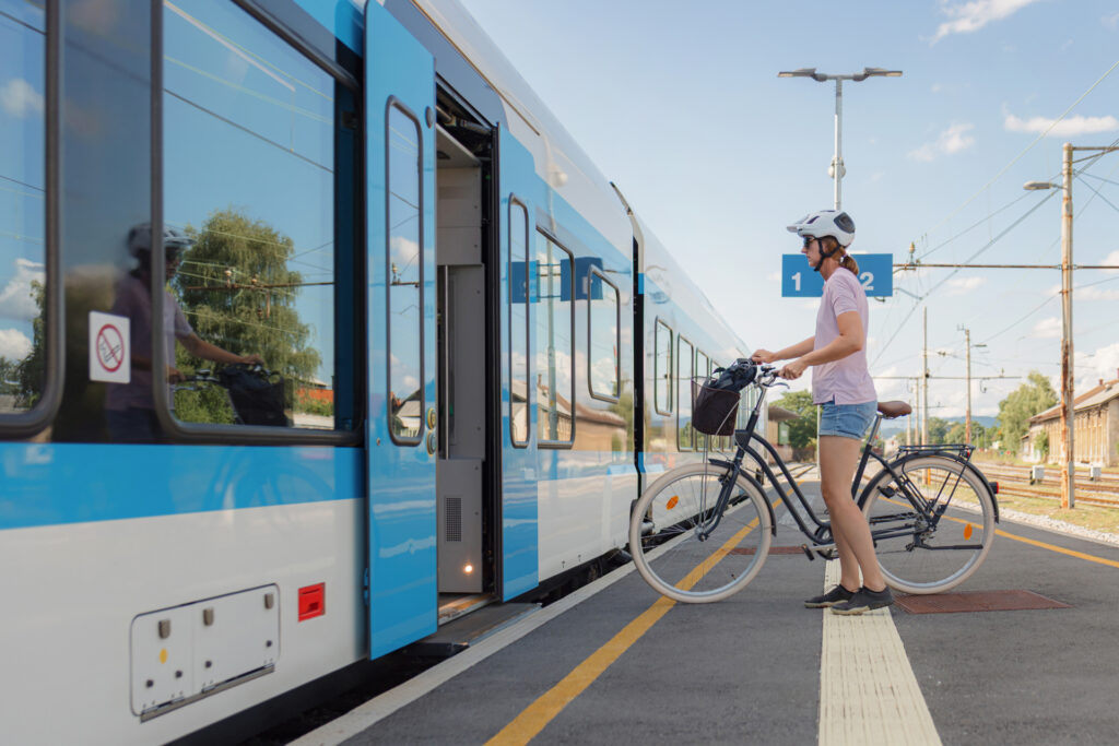 une femme attend avec son vélo pour rentrer dans un train TER sur le quai