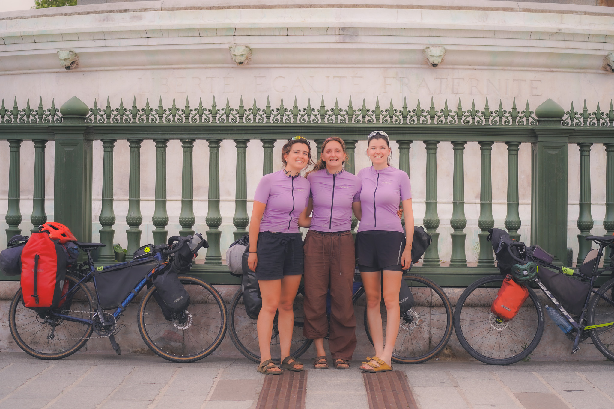 Trois jeunes femmes habillées en violet devant trois vélos