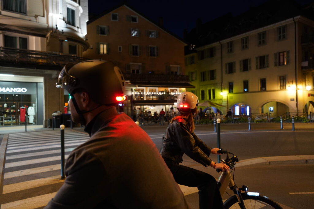 deux cyclistes en ville de nuit, avec leurs casques intégrant des lumières LED à l'arrière