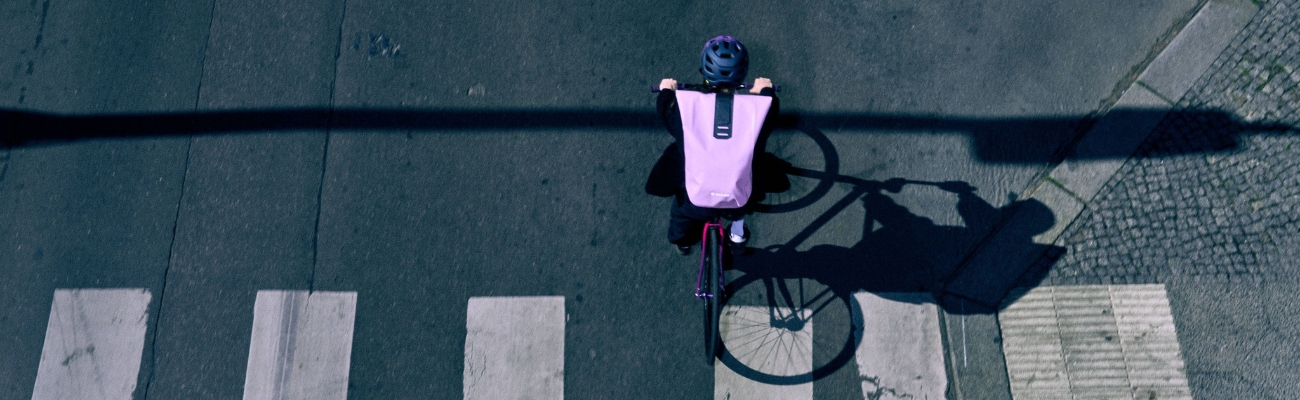 Personne à vélo avec un sac ORTLIEB couleur lavande sur le dos